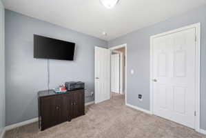 Bedroom featuring light carpet and baseboards