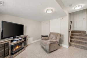 Sitting room with dark speckled floor, a textured ceiling, and a warm lit fireplace