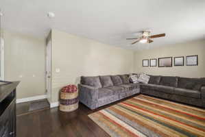 Living area featuring dark wood-style floors and ceiling fan
