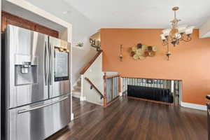 Kitchen with stainless steel refrigerator with ice dispenser, dark wood-style floors, and hanging lights