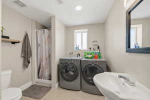 Bathroom with dark aggregate flooring, a stall shower, and washer and dryer