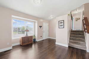 Foyer with stairs and dark wood-style flooring