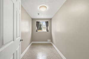 Spare room featuring a textured ceiling and dark speckled floor