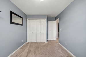 Unfurnished bedroom with carpet, a closet, and a textured ceiling