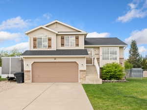 Split level home with an attached garage, driveway, and brick siding