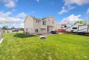 Rear view of property with a gate, a hot tub, a fenced backyard, and a patio area