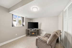 Living room featuring a glass covered fireplace and dark aggregate flooring
