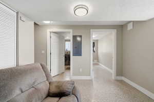 Living area featuring electric panel, washer / clothes dryer, dark speckled floor, and a textured ceiling