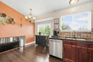 Kitchen featuring dishwasher, dark stone countertops, tasteful backsplash, dark wood finished floors, and suspended lighting