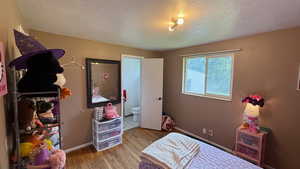 Bedroom featuring light wood finished floors, a textured ceiling, and ensuite bath