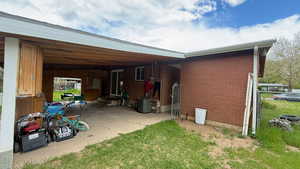 Back of house with entry steps, a patio area, brick siding, and a carport