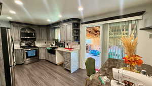 Kitchen featuring open shelves, stainless steel appliances, dark wood-style flooring, light stone countertops, and backsplash