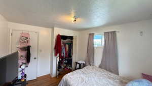 Bedroom with a closet, a textured ceiling, and dark wood-style floors