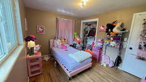 Bedroom with a textured ceiling, wood finished floors, and a closet