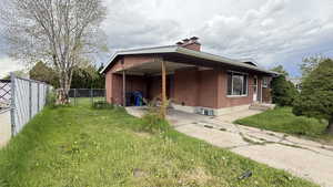 View of property exterior featuring brick siding, a chimney, and a patio