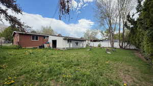 Back of property featuring a fenced backyard, a chimney, and brick siding