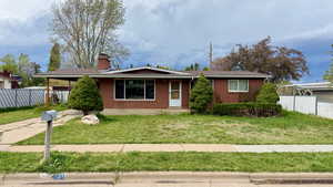 Ranch-style house with a carport, brick siding, and a chimney