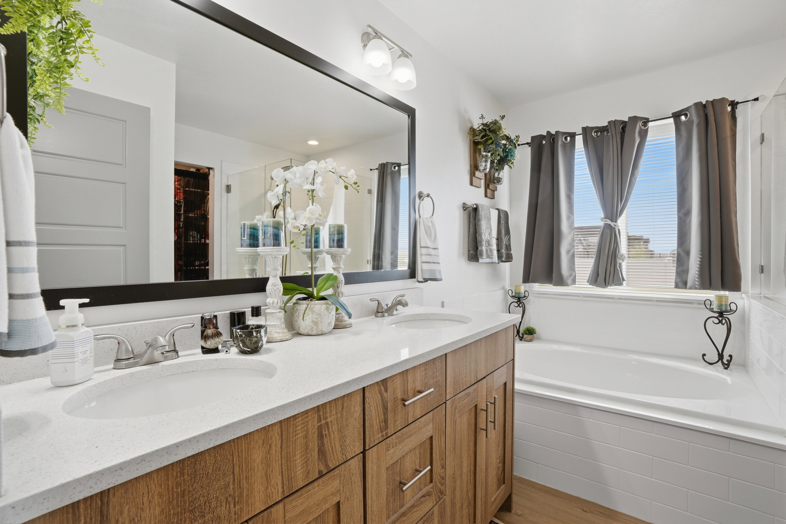 Bathroom with double vanity, a bath, and light wood finished floors