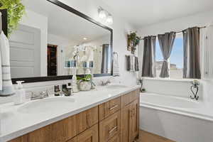 Bathroom with double vanity, a bath, and light wood finished floors