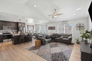 Living area featuring ceiling fan, light wood-type flooring, vaulted ceiling, and recessed lighting