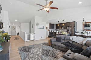 Living room featuring light wood-style flooring, recessed lighting, a ceiling fan, and vaulted ceiling