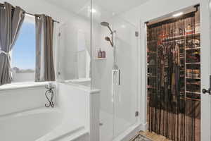 Bathroom featuring a spacious closet, a stall shower, and a bath