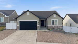 View of front of house with a gate, stone siding, concrete driveway, a garage, and stucco siding