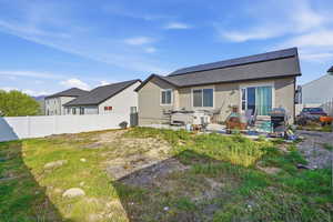 Rear view of house featuring solar panels, a fenced backyard, a patio area, a shingled roof, and stucco siding