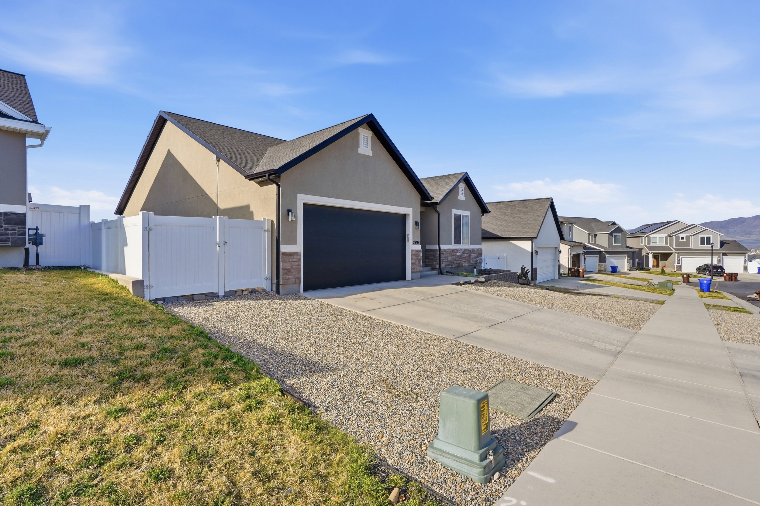 View of front facade featuring a gate, concrete driveway, a garage, a residential view, and stucco siding