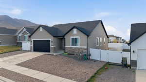 View of front of property featuring a gate, stone siding, driveway, stucco siding, and a garage