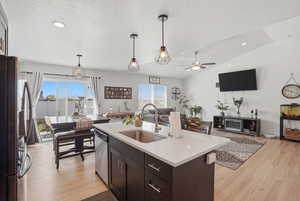 Kitchen featuring open floor plan, stainless steel appliances, hanging light fixtures, and light wood-type flooring