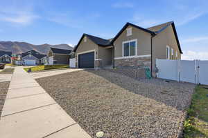 View of front of home with a gate, stone siding, driveway, stucco siding, and a garage