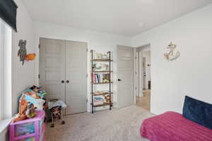 Bedroom featuring light carpet and a closet
