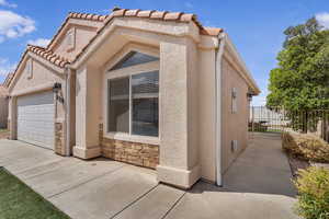 View of front of home with an attached garage, stucco siding, stone siding, and concrete driveway