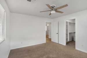 Unfurnished bedroom featuring carpet, a ceiling fan, and a spacious closet