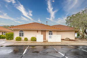 View of front of property featuring stucco siding, uncovered parking, and a tiled roof