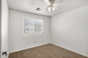 Carpeted empty room featuring ceiling fan and a textured ceiling