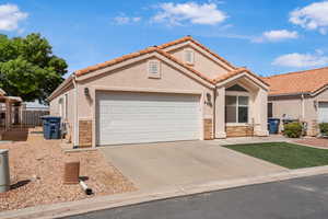 Mediterranean / spanish-style house with stone siding, driveway, an attached garage, stucco siding, and a tile roof