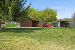 View of green lawn featuring a pole building and an outdoor structure