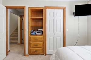 Bedroom with light colored carpet and a closet