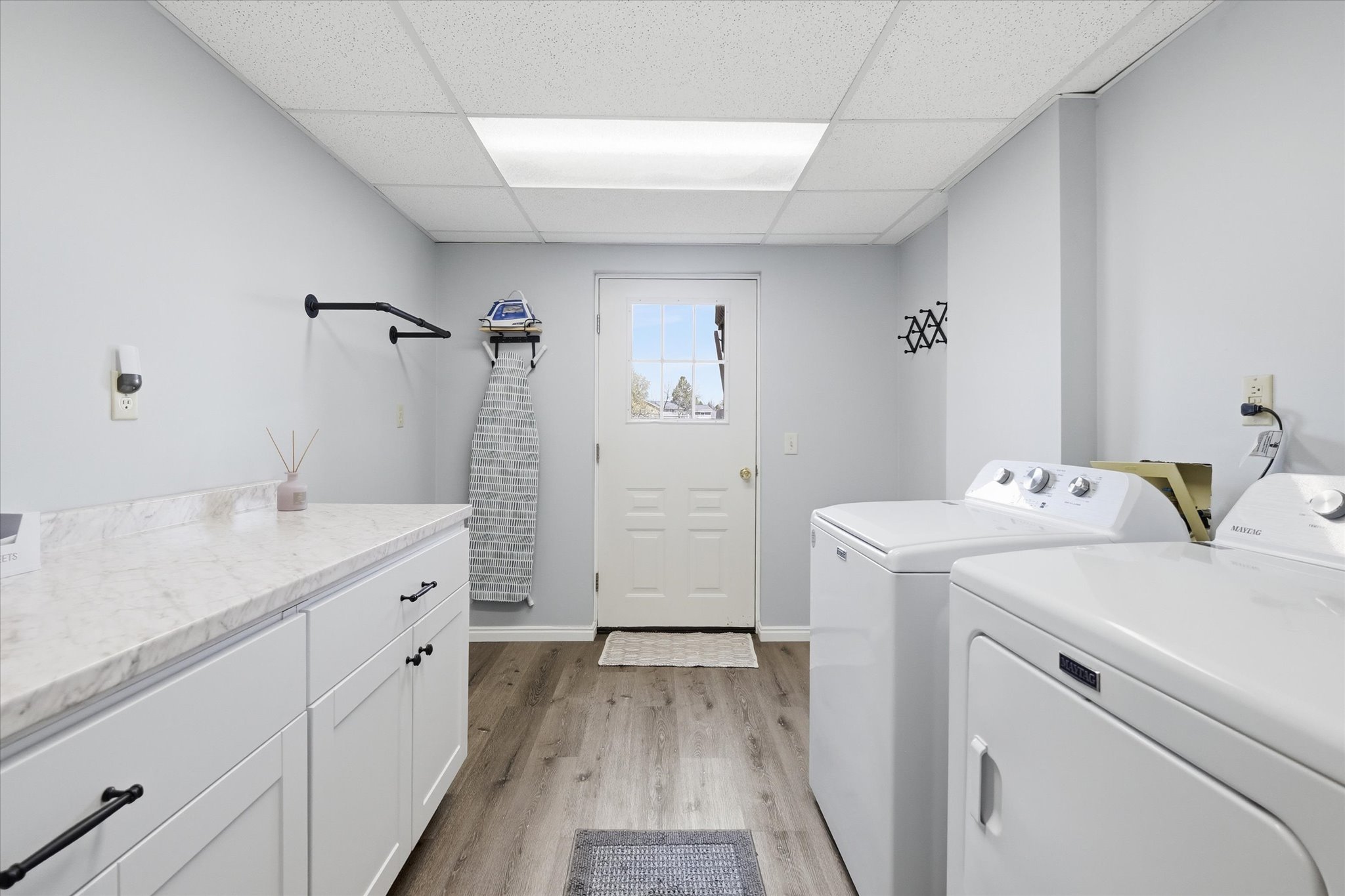 Laundry area with light wood-style flooring, a drop ceiling, separate washer and dryer, and cabinet space