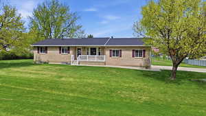 Ranch-style home with a front lawn, brick siding, and covered porch