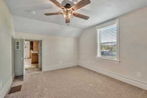 Unfurnished bedroom featuring lofted ceiling, light carpet, and a ceiling fan