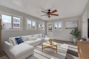 Living area with ceiling fan, baseboard heating, and wood finished floors