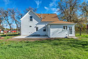 Rear view of house with a shingled roof and a patio area