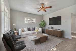 Carpeted living room featuring ceiling fan and baseboards