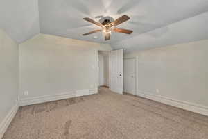 Bonus room with lofted ceiling, carpet, and ceiling fan