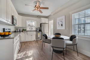 Kitchen with stainless steel appliances, white cabinetry, a ceiling fan, and light wood-style flooring