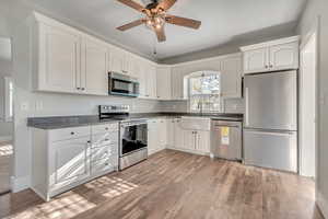 Kitchen featuring stainless steel appliances, ceiling fan, and white cabinetry