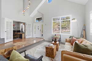 Living area with lofted ceiling, wood finished floors, a desk, and french doors